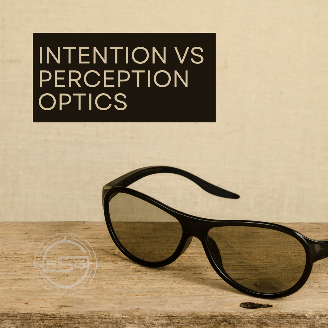 A pair of black sunglasses on the the edge of a table with a beige wall in the background. A brown rectangular bar with text inside that reads Intention VS Perception Optics. In the lower left corner is a watermark of the FSG logo in white. The logo has the letters FSG in the middle with a circle with four pointed arrows facing north, south, east and west with the S connected to that circle. Four rounded lines make the next circle of the circle and the last layer is a thin circle with the text on the Bottom that reads Stewarding Strategist Solutions and on top, the text reads Fish Stewarding Group.
