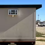 An outside view of the side of a tan colored FSG Living Buildings MUPPS Tiny Home