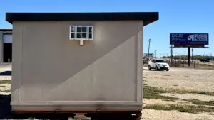 An outside view of the side of a tan colored FSG Living Buildings MUPPS Tiny Home